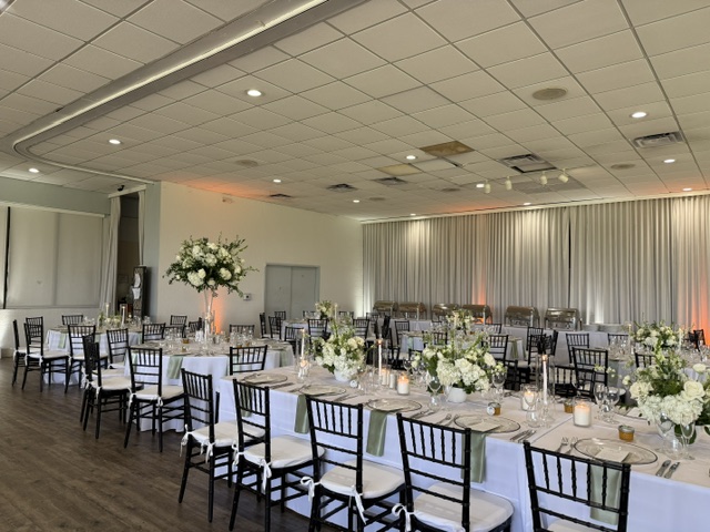 Round banquet table with tropical centerpiece and black charger plates